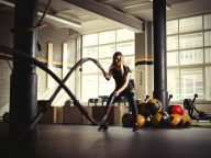 Woman training with battle ropes in gym