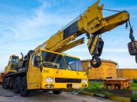 Yellow mobile crane against fuel oil storage tank area in power
