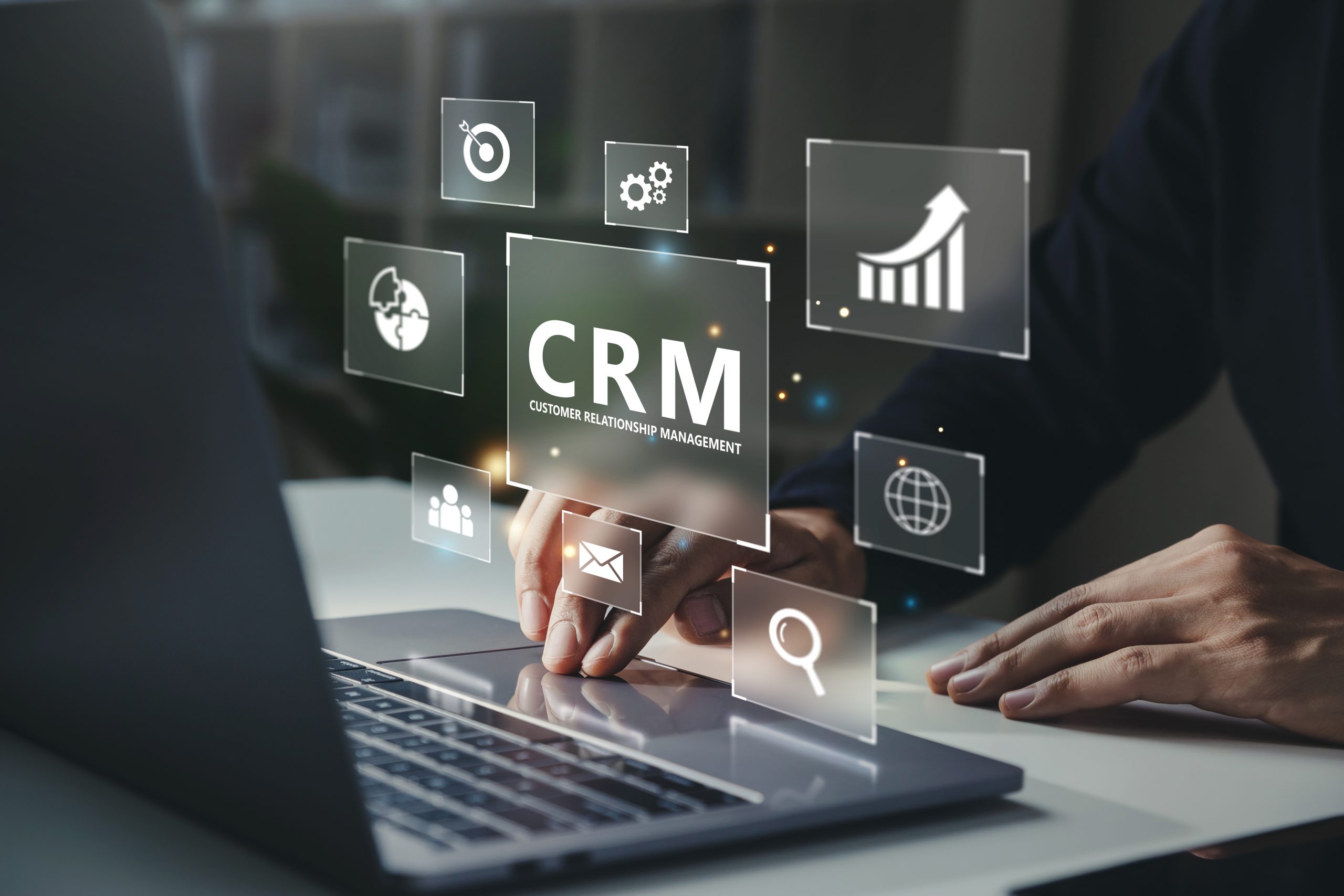 Businessman using laptop with CRM icon on virtual screen.