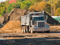 A dump truck about to unload a pile of dirt