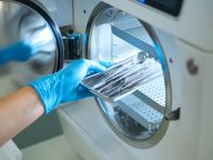 Woman hand in gloves puts dental instrument into sterilization apparatus
