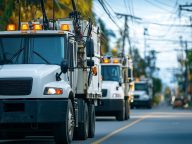 White utility trucks driving on a street.
